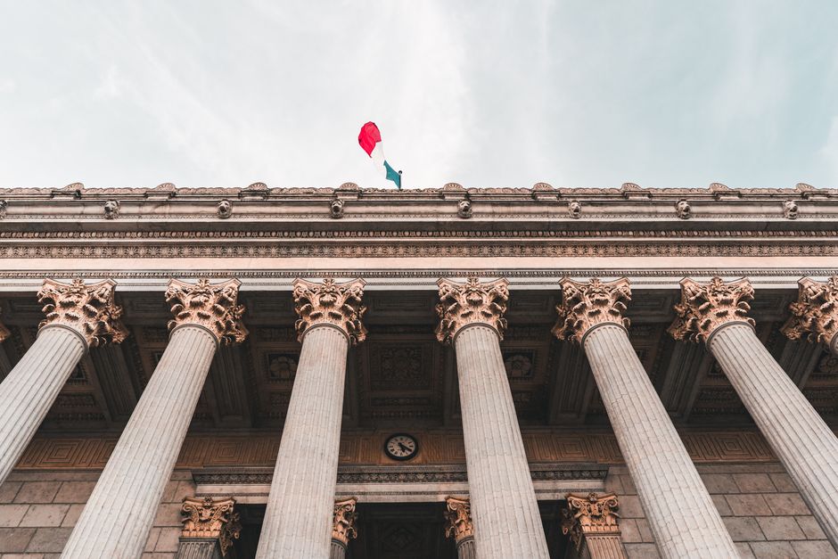 Majestic neoclassical columns of a grand government palace with a flag atop.