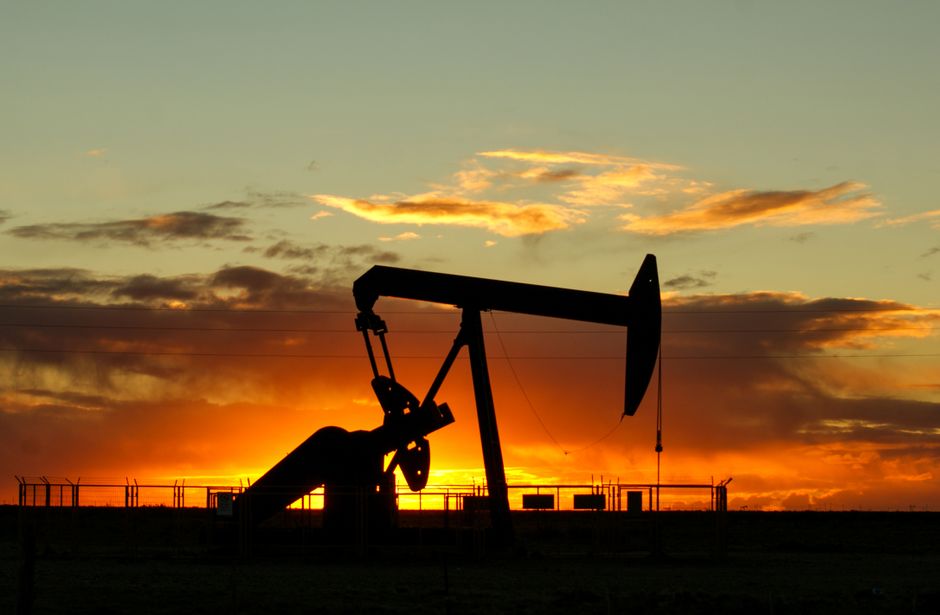 Silhouette of an oil pump jack against a vibrant sunset sky