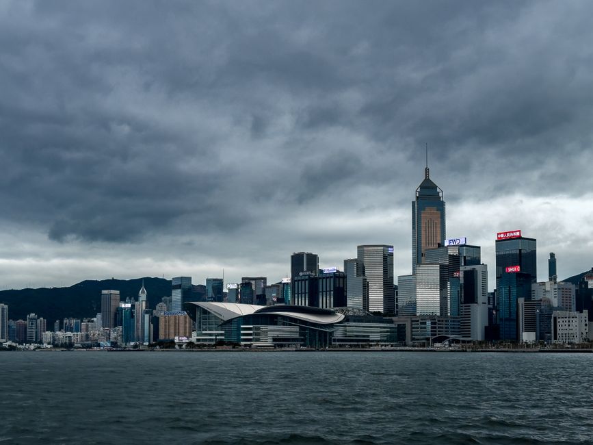 Hong Kong's financial district skyline under a dramatic sky.