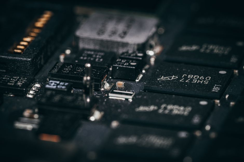 Macro view of electronic circuit components on a green substrate, showing intricate semiconductor design and layout.