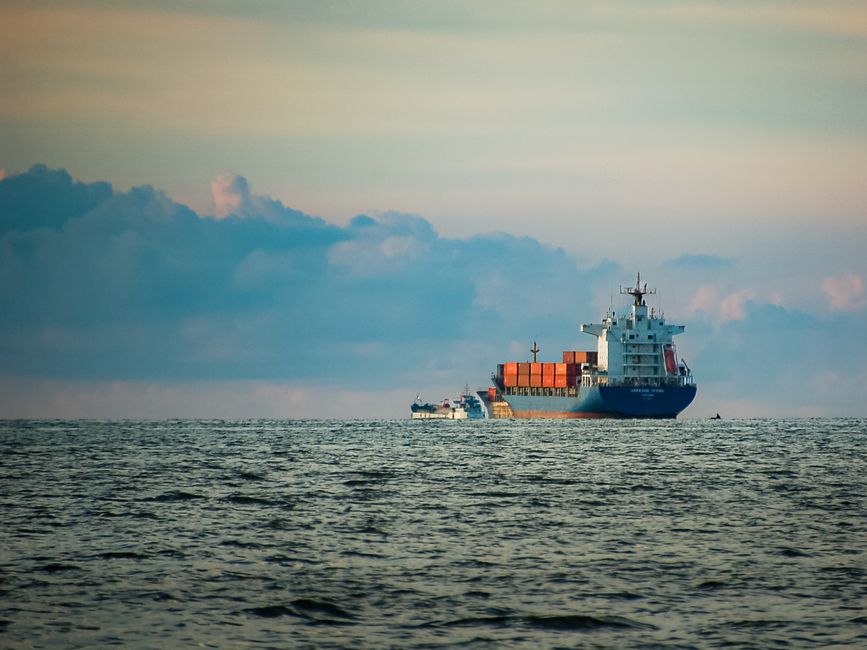 A container ship sailing on the open sea at dusk.