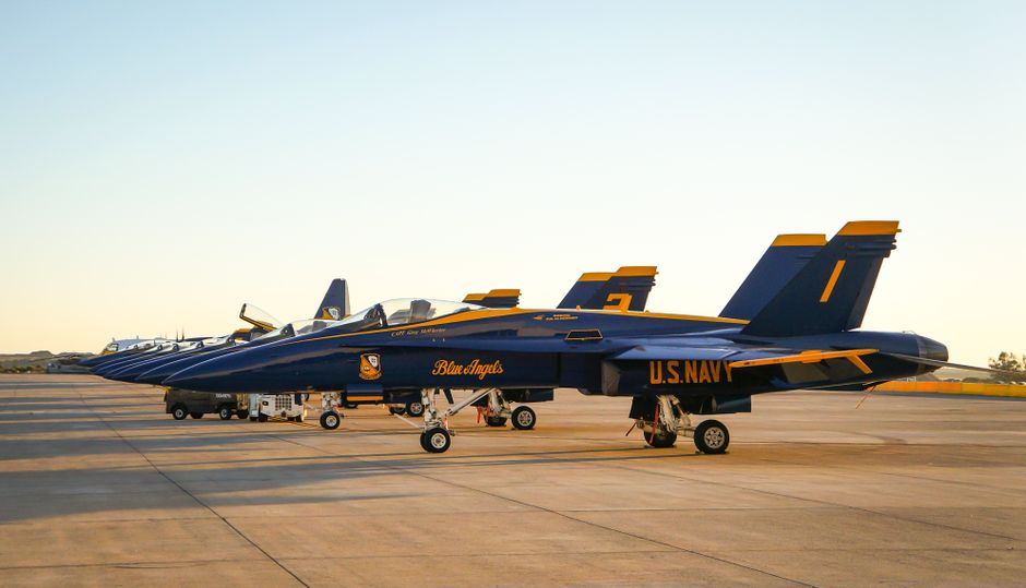 Military fighter jets lined up on a runway at dusk