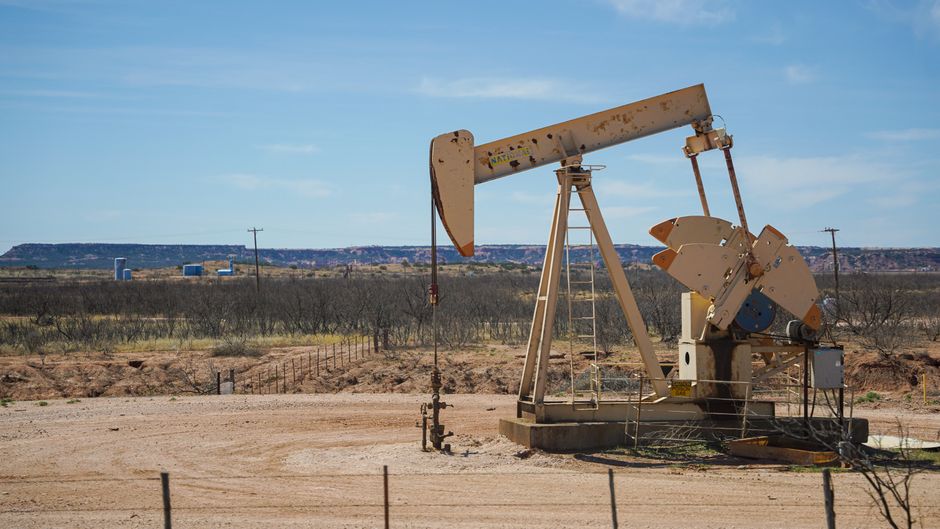 Industrial oil pumpjack in a desert landscape under a clear sky, symbolizing petroleum extraction and energy markets
