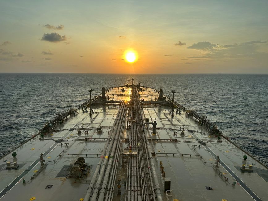 A large oil tanker sailing on the ocean at sunset, symbolizing vulnerable shipping traffic through the Strait of Hormuz.