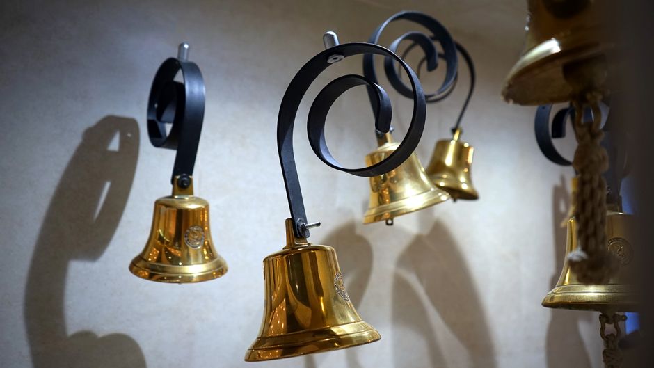 Golden ceremonial bells hanging against a dark wall, symbolizing the IPO bell-ringing tradition at stock exchanges