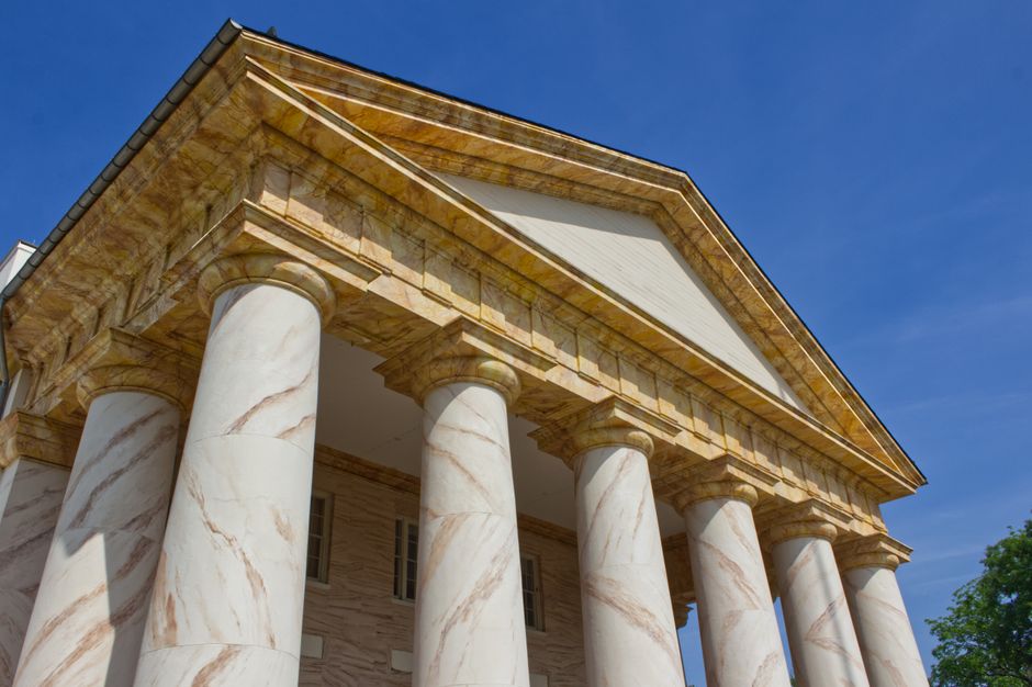 Low-angle view of a neoclassical government building with grand columns against a clear sky, symbolizing US fiscal and monetary institutions under pressure.