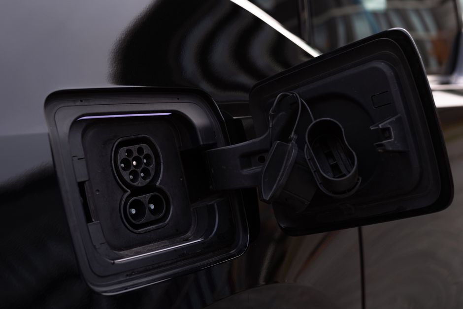 Close-up of an electric vehicle charging port on a dark vehicle