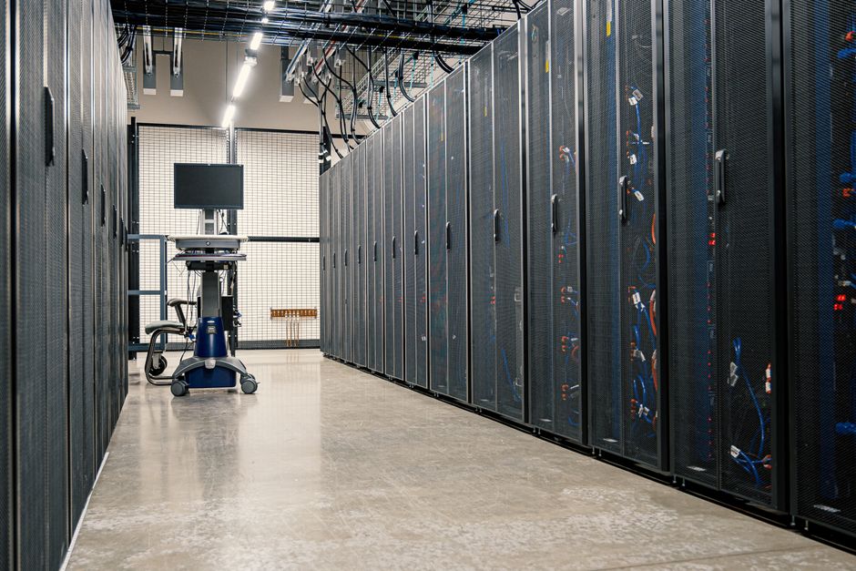 Rows of server racks with networking cables and equipment in a modern data center.