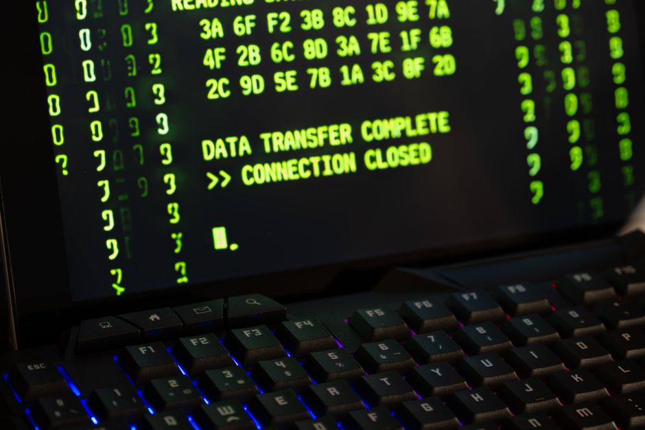 Data transfer screen displayed on a computer monitor with a keyboard, representing digital infrastructure and network security.