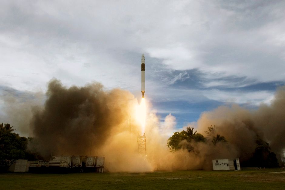 Rocket lifting off through clouds of smoke against an overcast sky