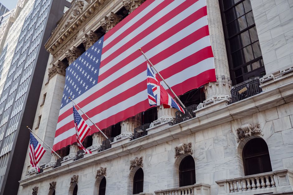 American flag flying above a historic institutional building facade, photographed from a low angle.