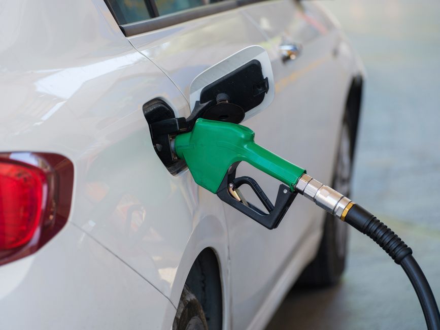 Close-up of a fuel pump nozzle refueling a white car at a gas station