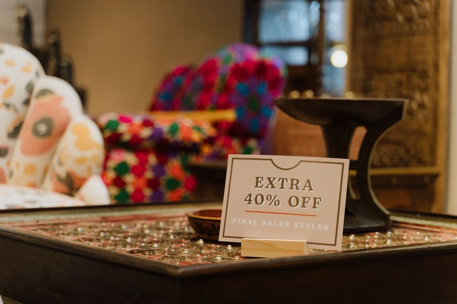 A retail display presents a sale sign in a warm, wood-toned store setting.