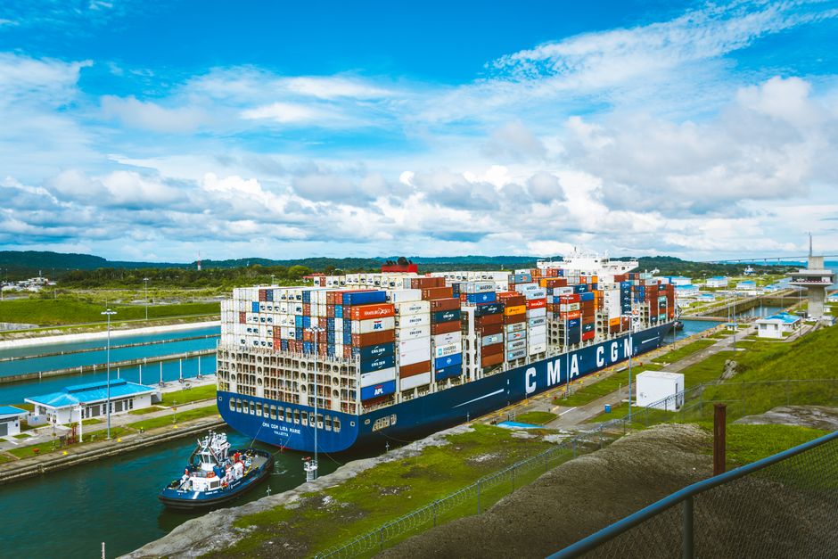 A large cargo ship at a docking area, symbolizing global trade routes squeezed by conflict at multiple chokepoints.