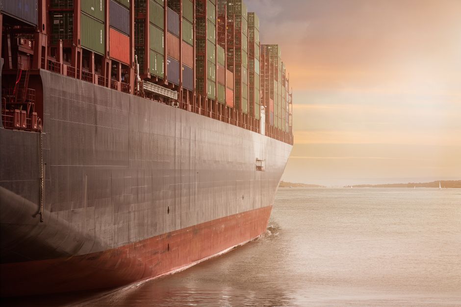 Container ship loaded with cargo sailing at sunset, representing the global logistics chains being rerouted around the Cape of Good Hope.