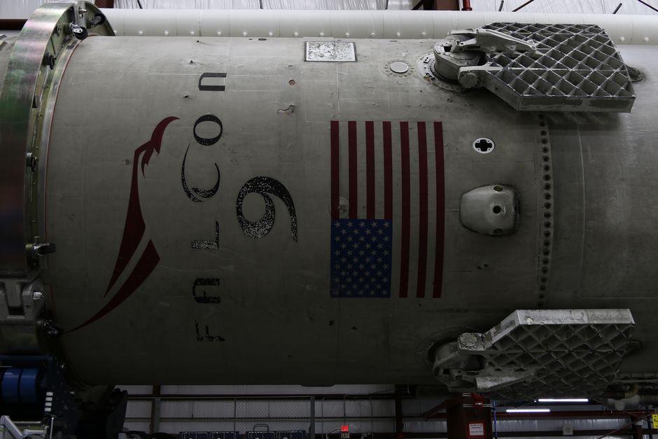 Fragment of a modern spacecraft under assembly in a rocket factory, with the American flag visible on a panel
