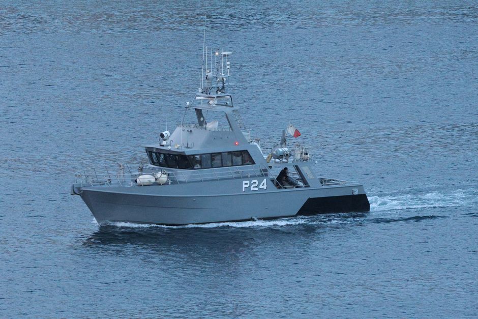 A navy patrol boat cruising through open ocean waters.