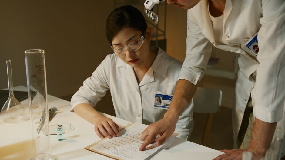 Researchers in lab coats reviewing experimental notes in a scientific setting.