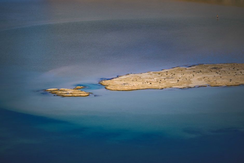 Aerial view of a small deserted sea islet in calm blue waters, evoking the strategic waterways of the Red Sea region