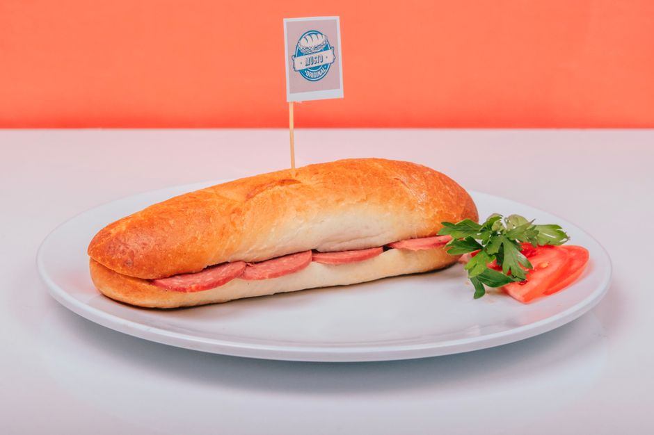 A sub sandwich with fresh garnish served on a plate at a deli or restaurant.
