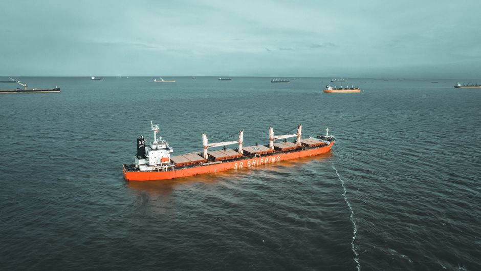 Aerial drone view of a large cargo ship navigating the open ocean.