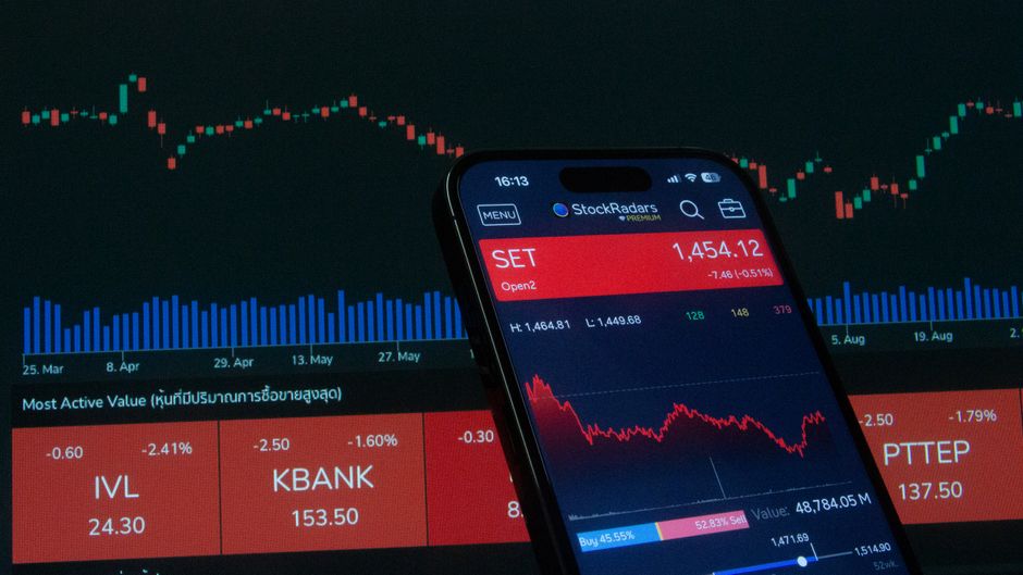 Mobile trading app displaying stock market data with charts on screen